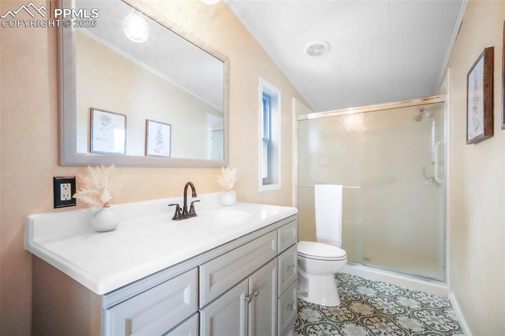 Full bath featuring vanity, a shower stall, ornamental molding, and light tile patterned floors