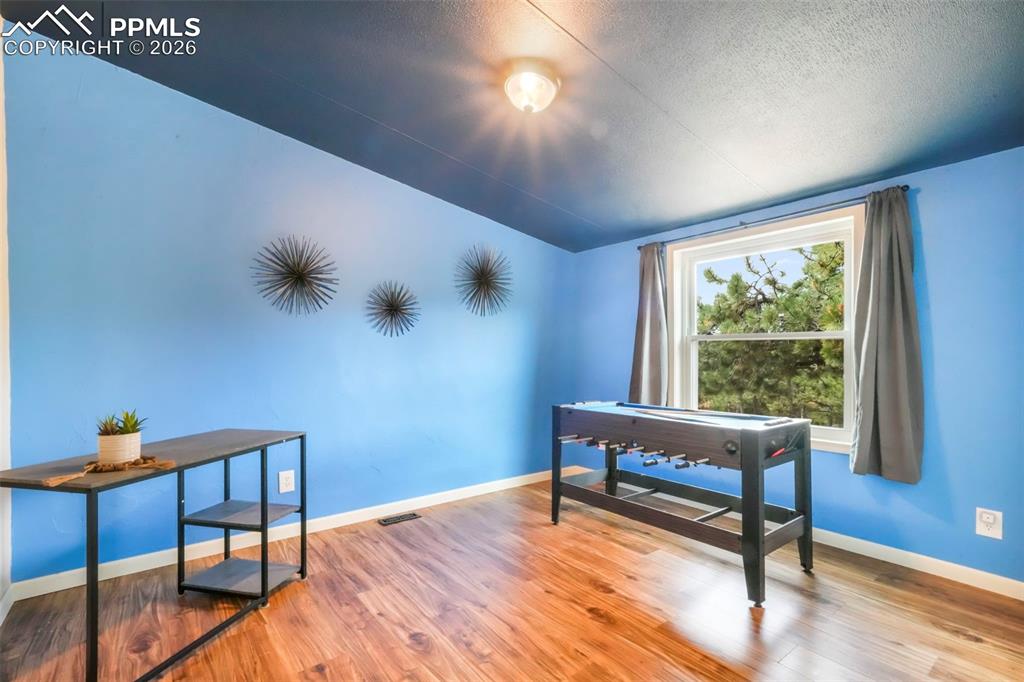 Office space featuring wood finished floors, a textured ceiling, and vaulted ceiling