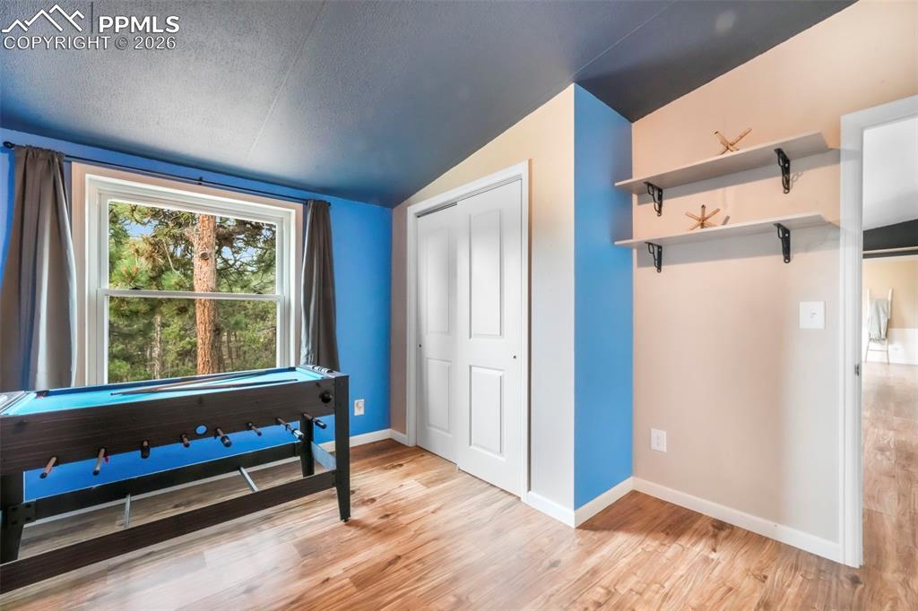 Misc room with a textured ceiling, lofted ceiling, and light wood-type flooring