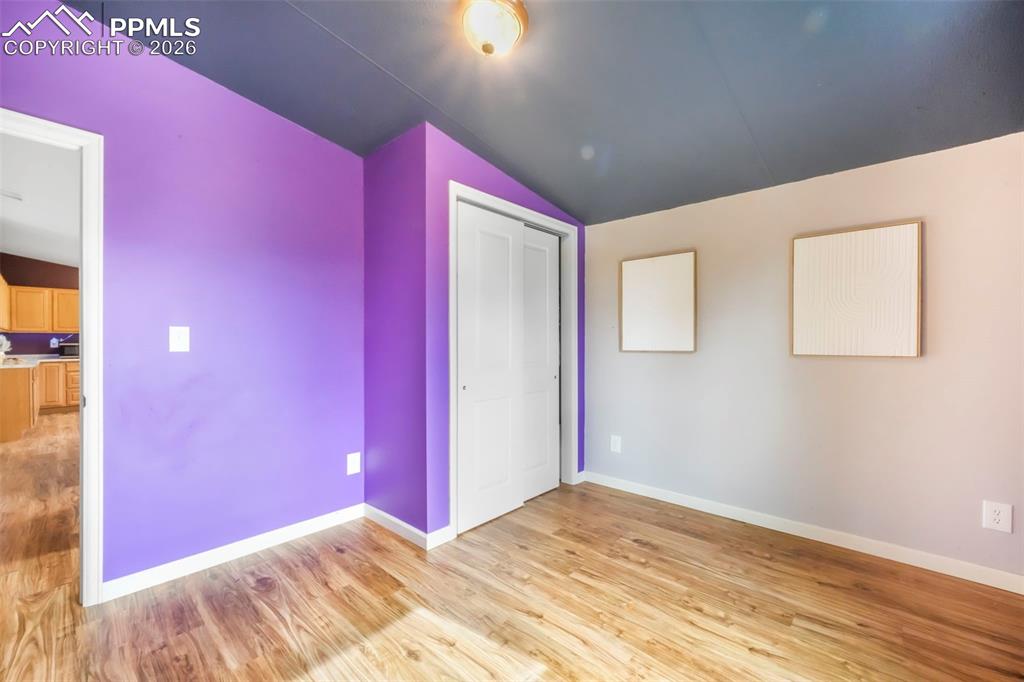Unfurnished bedroom with lofted ceiling, light wood-style flooring, and a closet