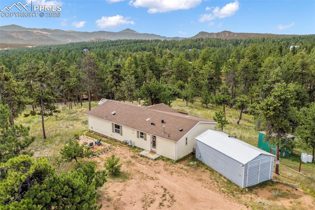 Aerial view of property and surrounding area featuring a forest and mountains