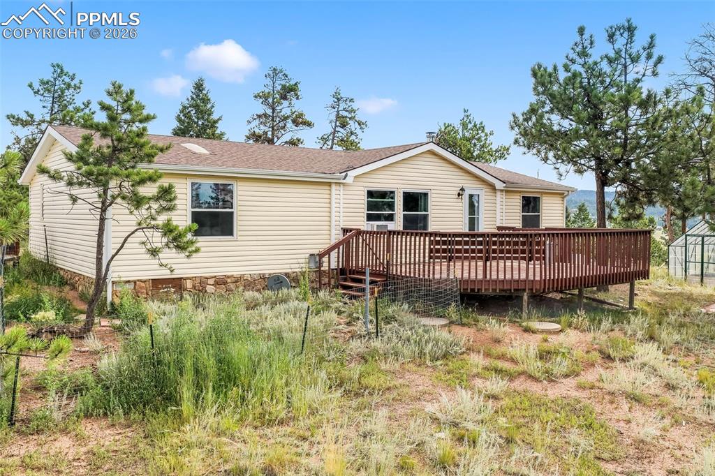 Rear view of property featuring a wooden deck and roof with shingles