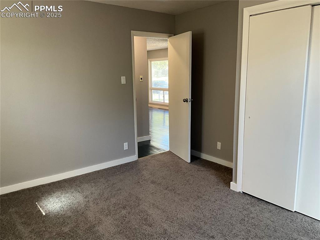 Unfurnished bedroom featuring dark colored carpet and a closet