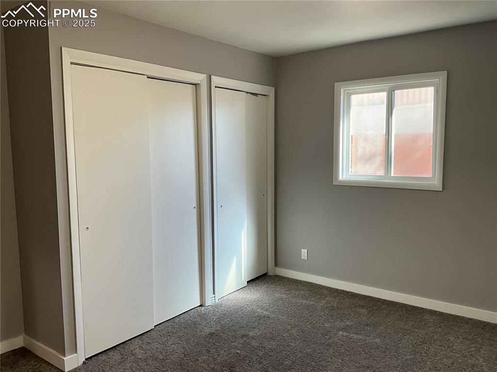 Unfurnished bedroom featuring new carpet flooring and two closets