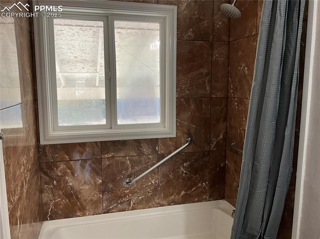 Bathroom with plenty of natural light and shower / bath combo with shower curtain