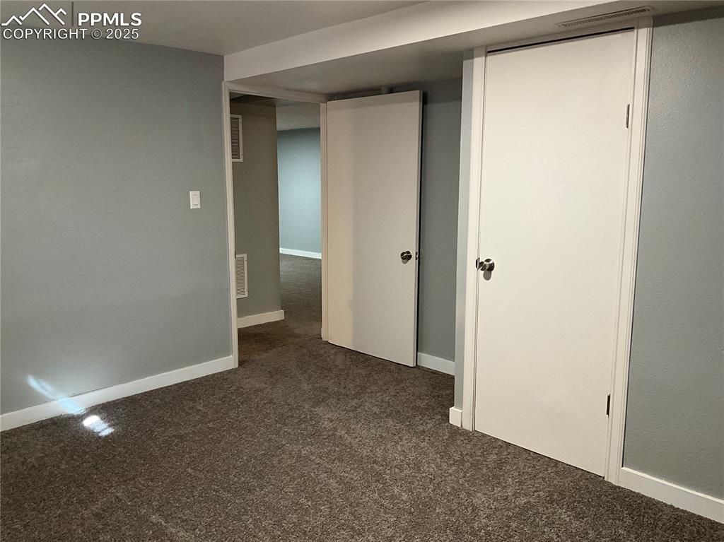 Unfurnished bedroom with dark carpet and baseboards