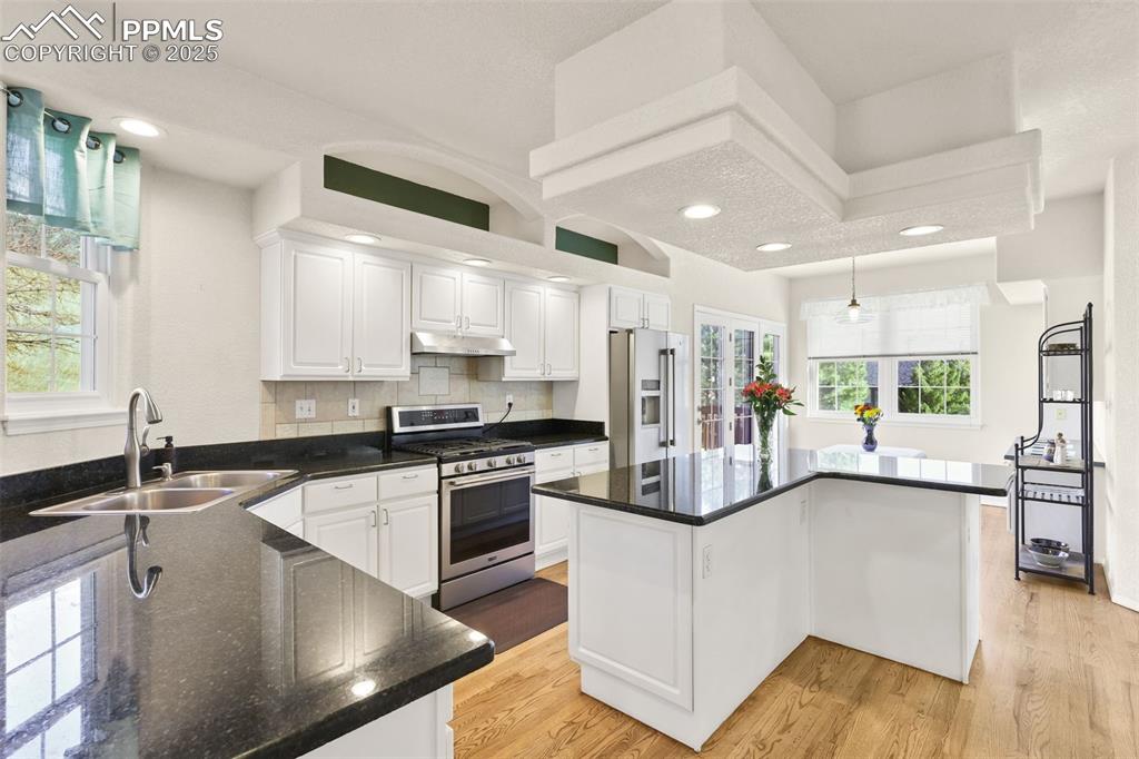 Kitchen featuring white cabinets, stainless steel appliances, a center island, light wood-type flooring, and recessed lighting