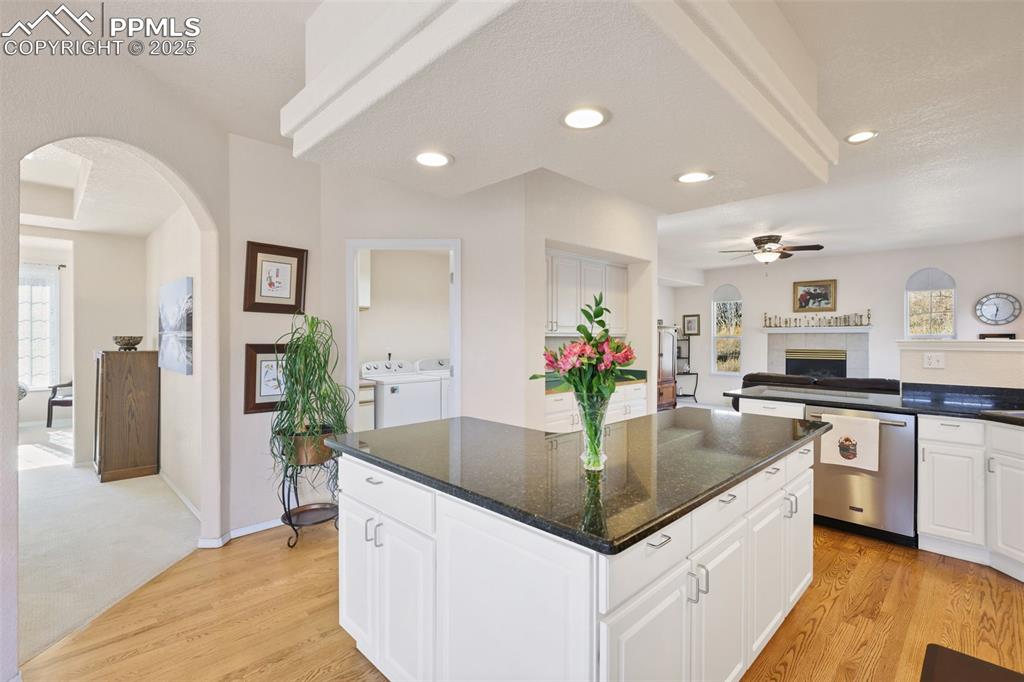 Kitchen with arched walkways, open floor plan, light wood-style flooring, ceiling fan, and dishwasher