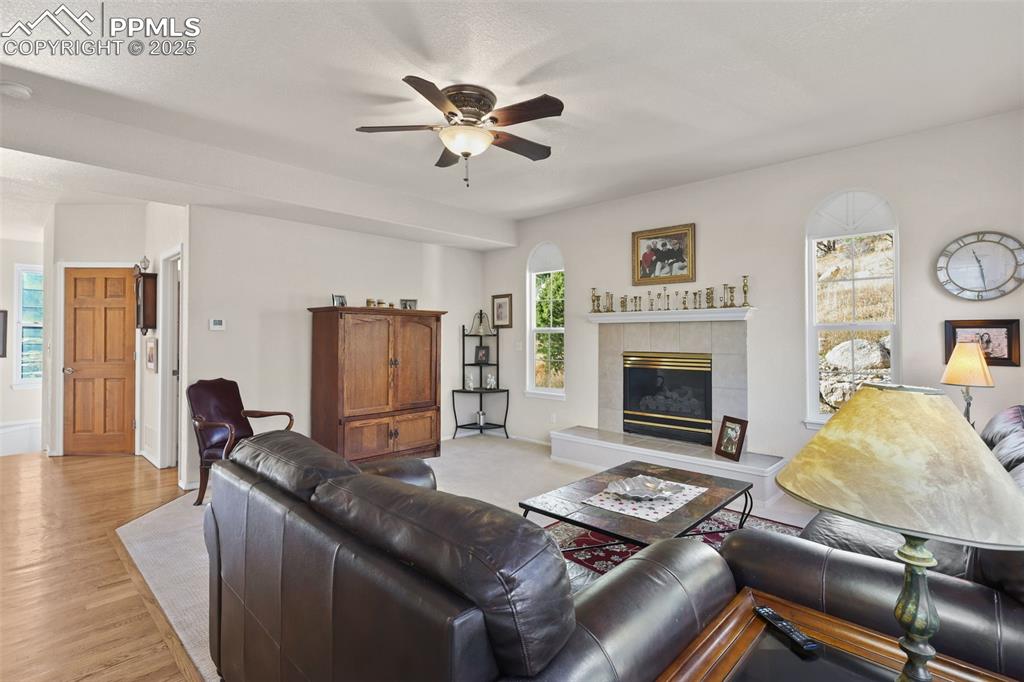 Living area featuring a tile fireplace, healthy amount of natural light, light wood-style flooring, and a ceiling fan