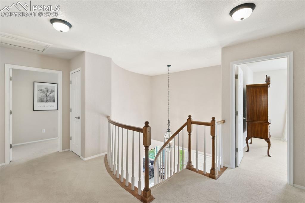 Hall with light carpet, an upstairs landing, and a textured ceiling