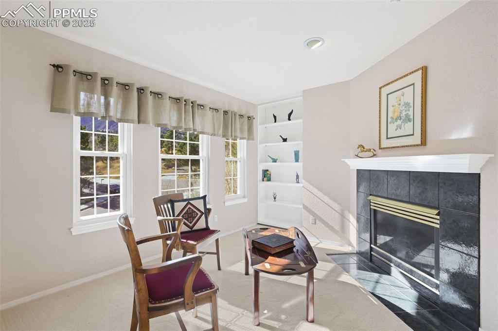 Sitting room featuring a tiled fireplace and carpet