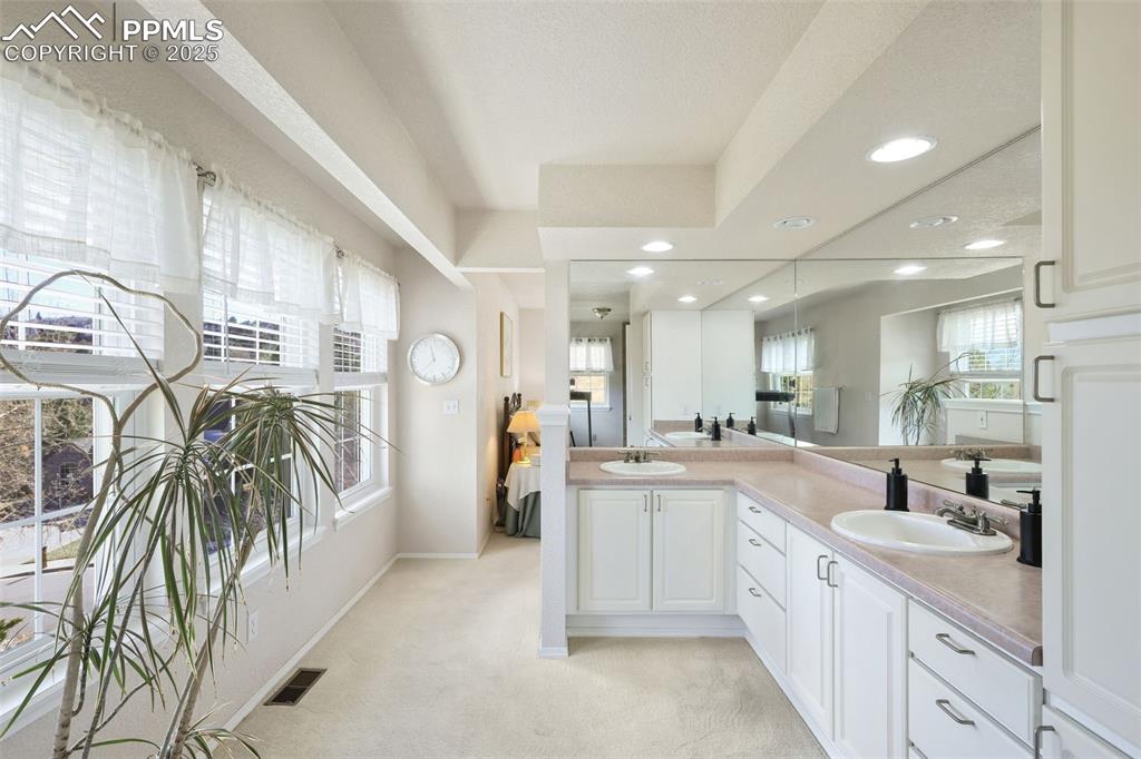 Full bathroom with double vanity, light colored carpet, and recessed lighting