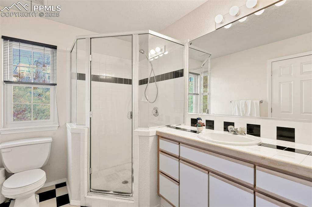 Bathroom featuring a shower stall, vanity, healthy amount of natural light, and light flooring