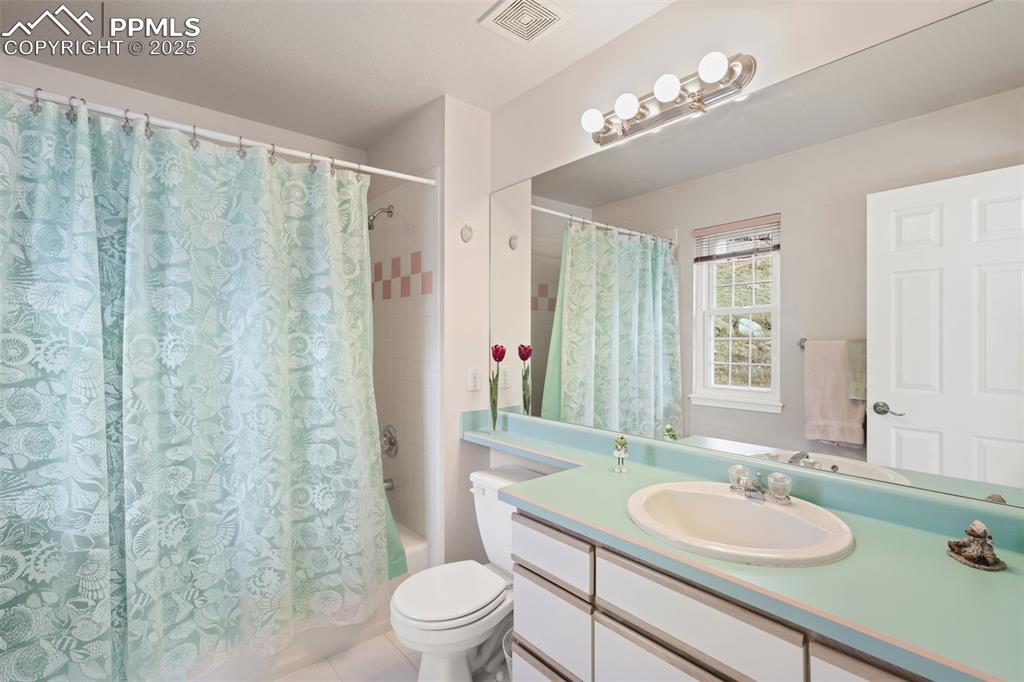 Full bath featuring shower / bath combo, vanity, and light tile patterned flooring