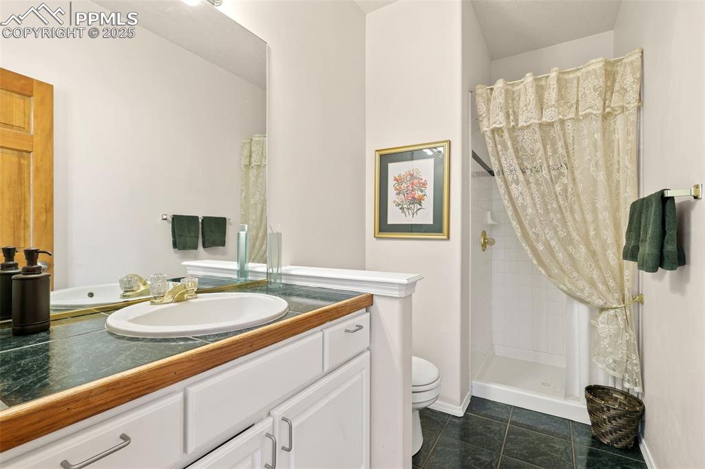 Bathroom with a shower stall, vanity, and dark tile patterned flooring