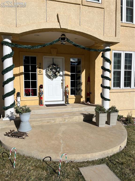 View of exterior entry featuring a porch and stucco siding
