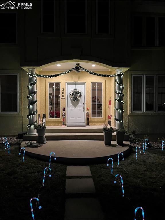 Exterior entry at night featuring stucco siding