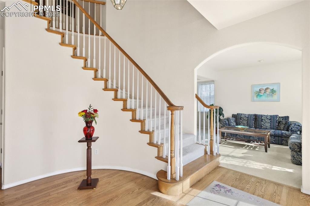 Stairway featuring wood finished floors, arched walkways, and a towering ceiling