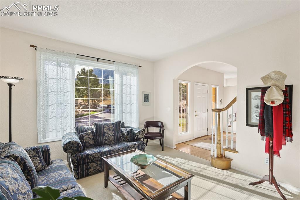 Carpeted living room featuring arched walkways and stairway