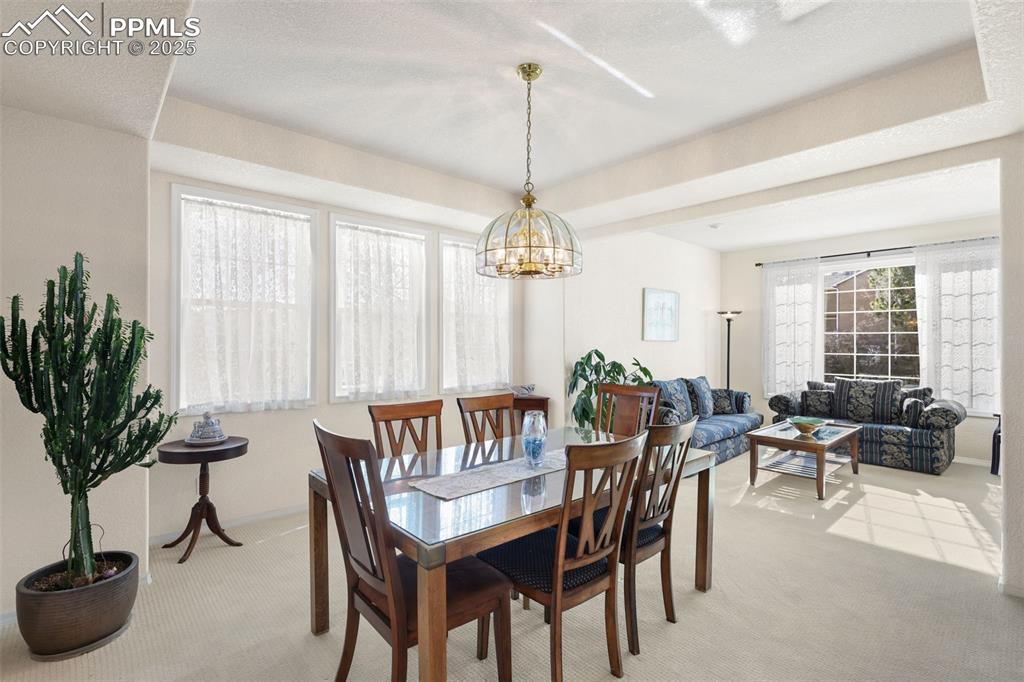 Dining space with light carpet and a chandelier