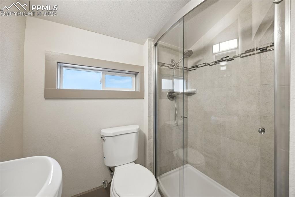 Bathroom featuring a shower stall, lofted ceiling, and a textured ceiling