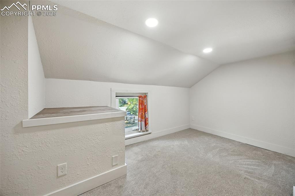 Bonus room featuring vaulted ceiling, light colored carpet, a textured wall, and recessed lighting