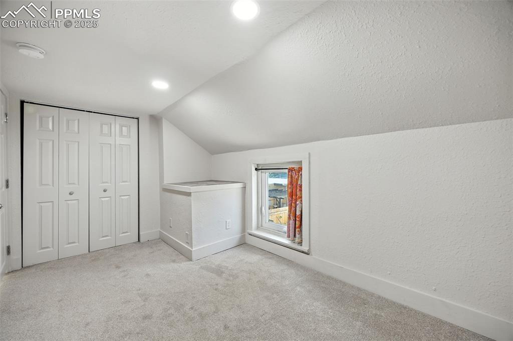 Bonus room with carpet, lofted ceiling, a textured ceiling, a textured wall, and recessed lighting