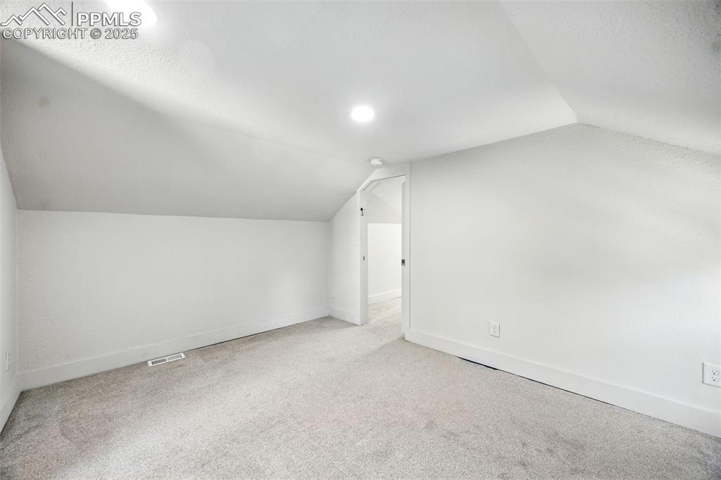 Additional living space with lofted ceiling and carpet
