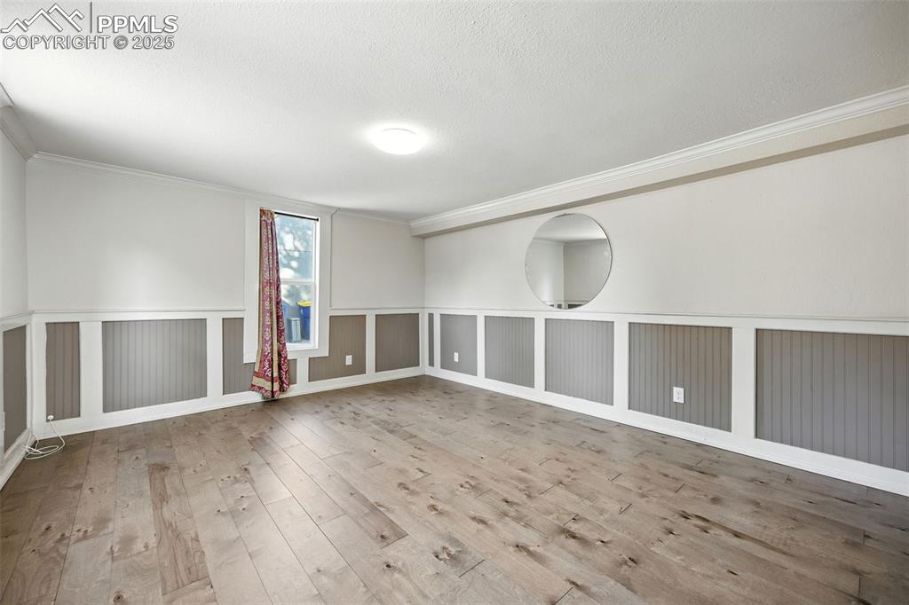 Spare room featuring ornamental molding, light wood-style floors, and a textured ceiling