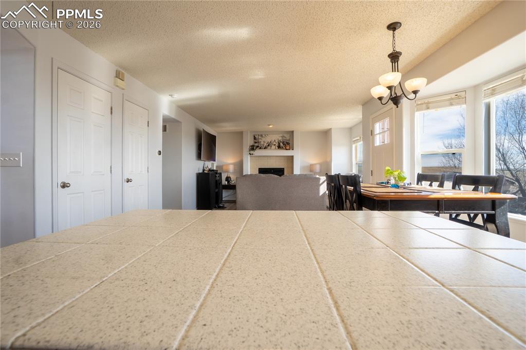 Dining space with a fireplace, a textured ceiling, and suspended lighting