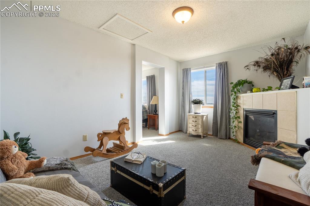 Carpeted living area with a tile fireplace and a textured ceiling