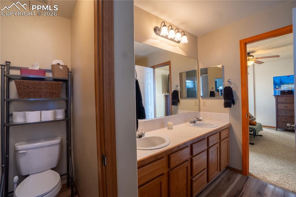 Bathroom with double vanity, dark wood-style flooring, and a ceiling fan