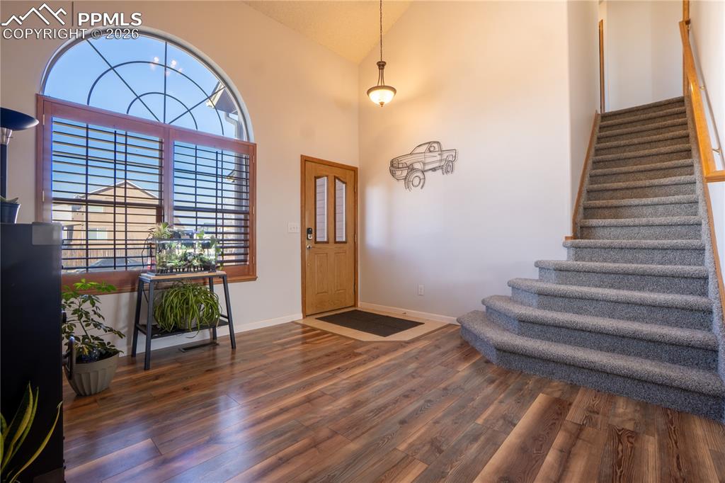 Entrance foyer with vaulted ceiling and dark wood-style floors