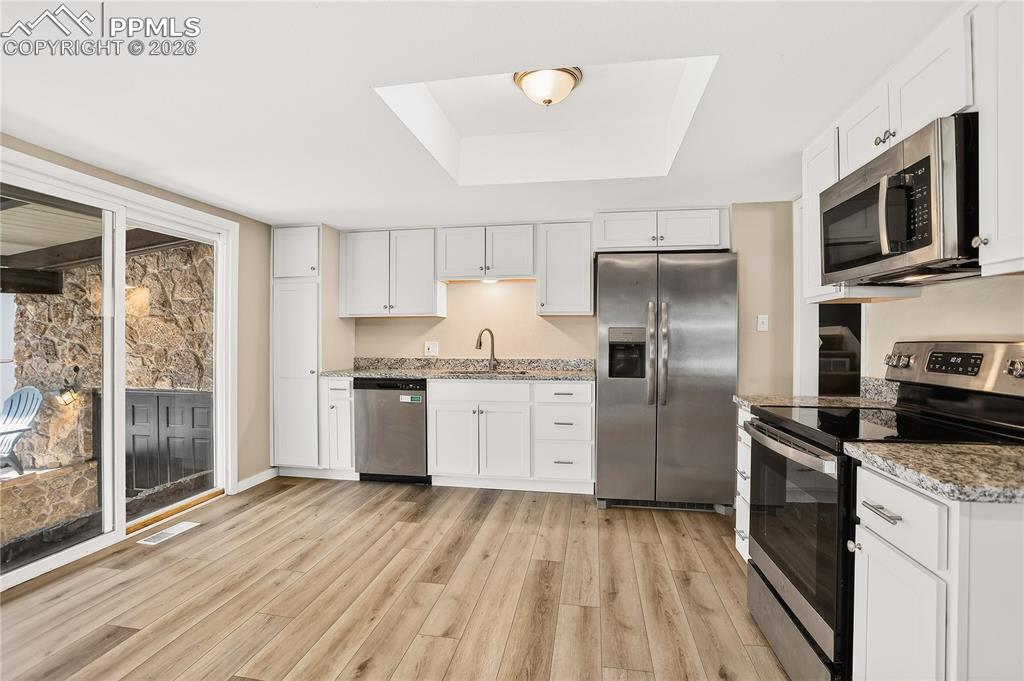 Kitchen with granite countertops, stainless steel appliances, and sliding door access to the covered patio.