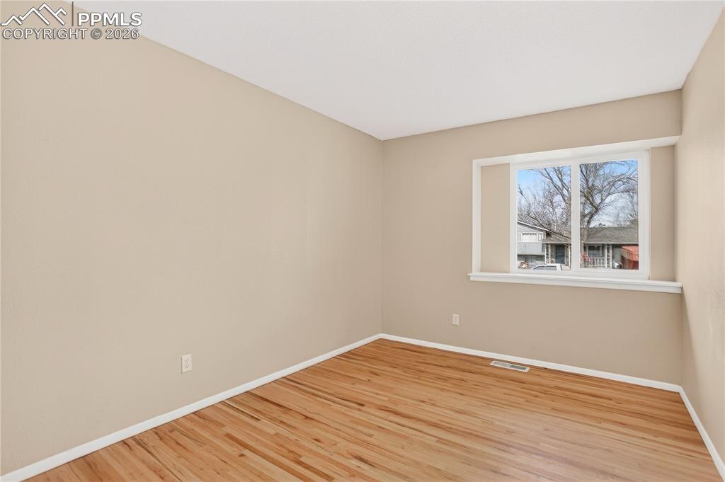 Second bedroom with hardwood flooring and natural light.