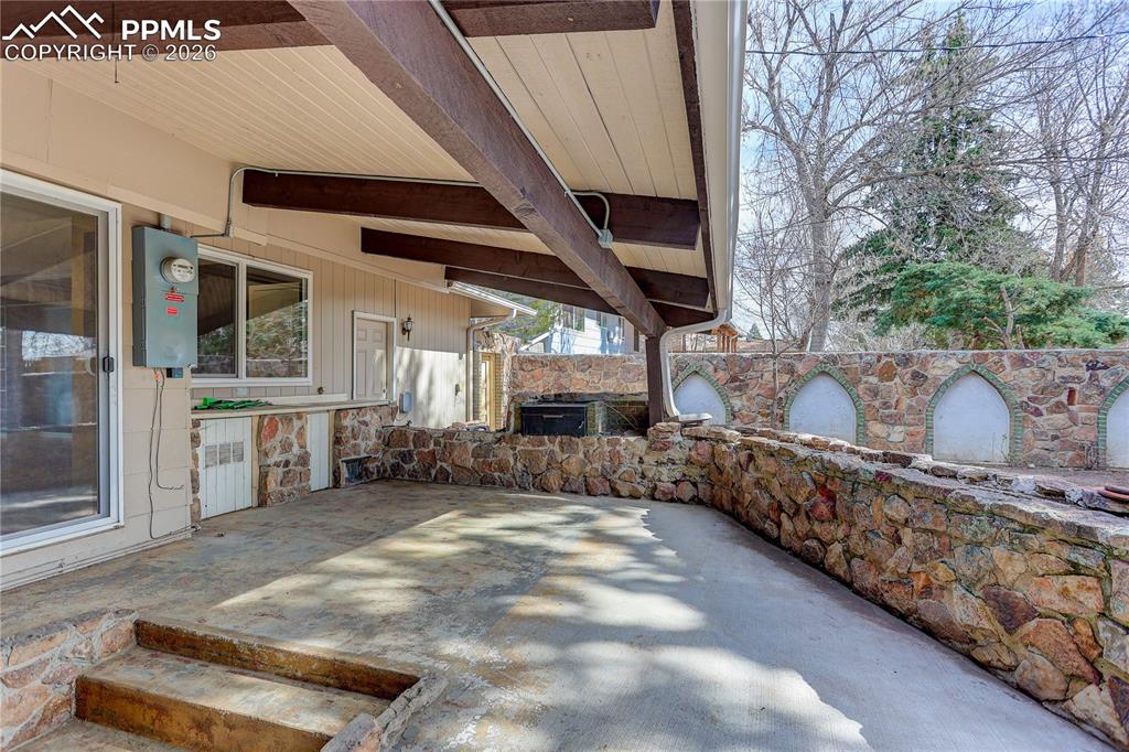 Covered patio space with stonework and outdoor grill.