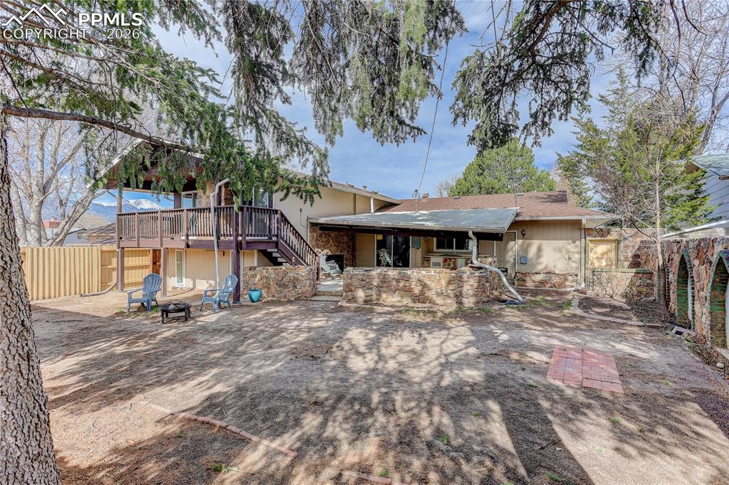 Rear view of home with deck, covered patio, and backyard space.