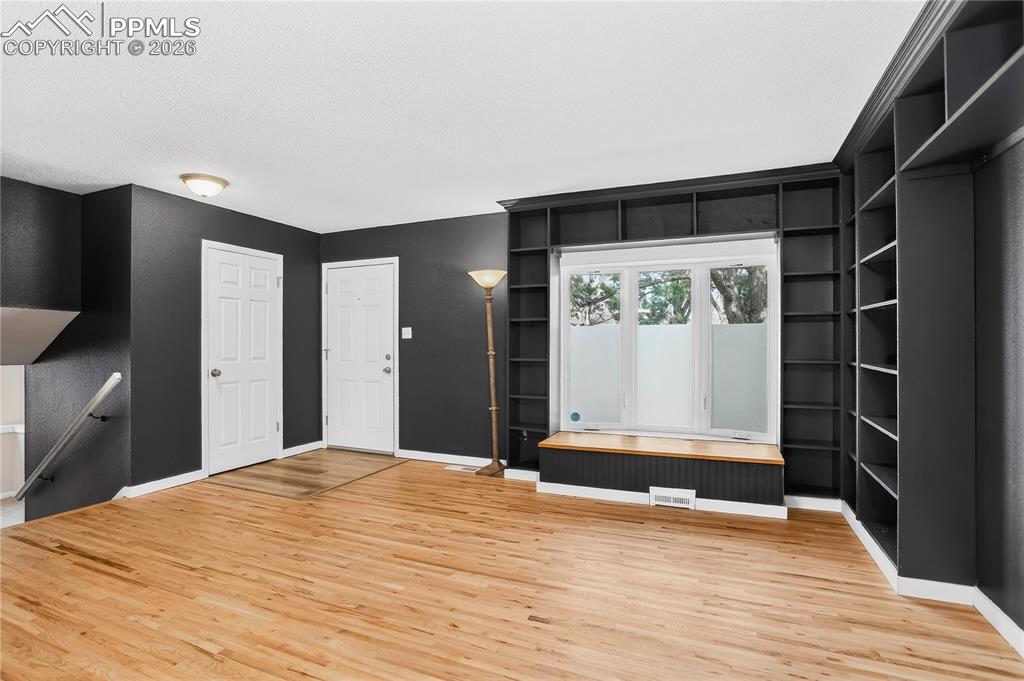 Living room with hardwood flooring, built-in shelving, and bay window with storage bench.