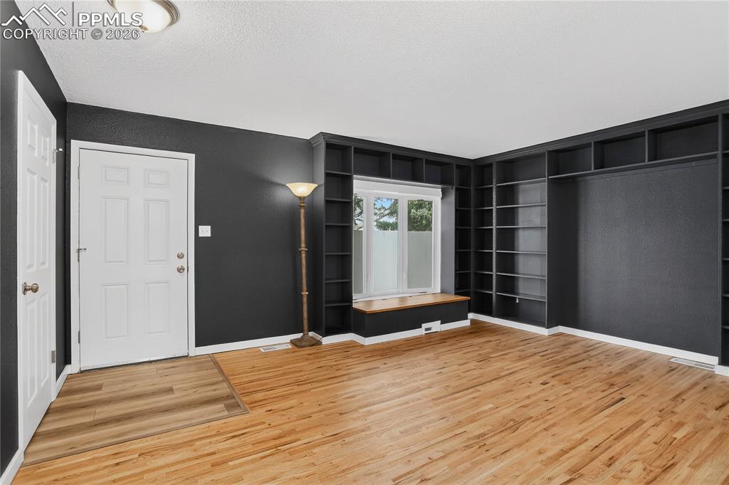 Living room with hardwood flooring, built-in shelving, and bay window with storage bench.
