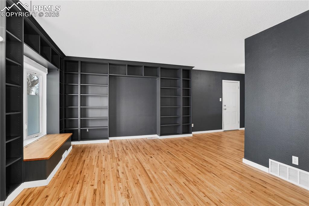 Living room with hardwood flooring, built-in shelving, and bay window with storage bench.
