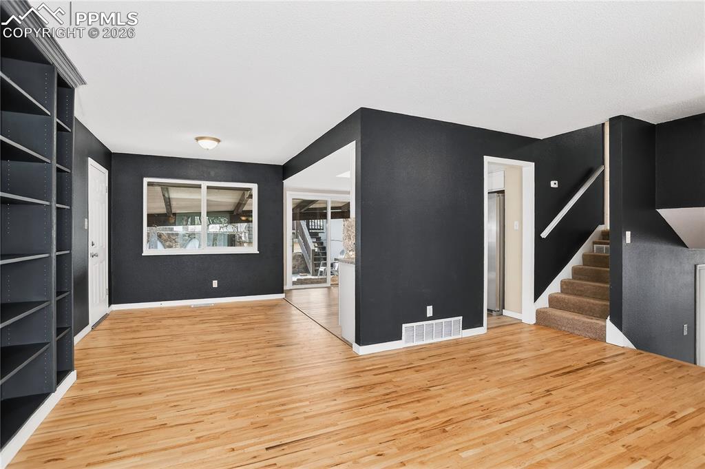 Unfurnished living room with stairway and light wood finished floors