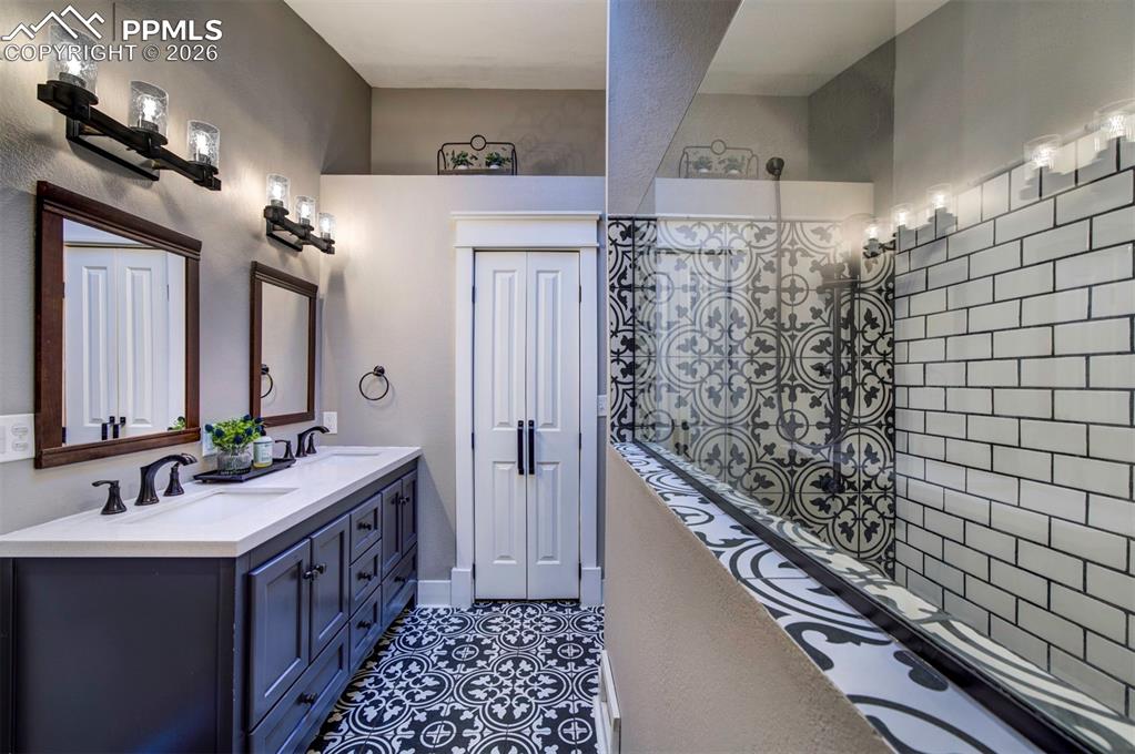 Bathroom featuring double vanity and dark tile patterned floors