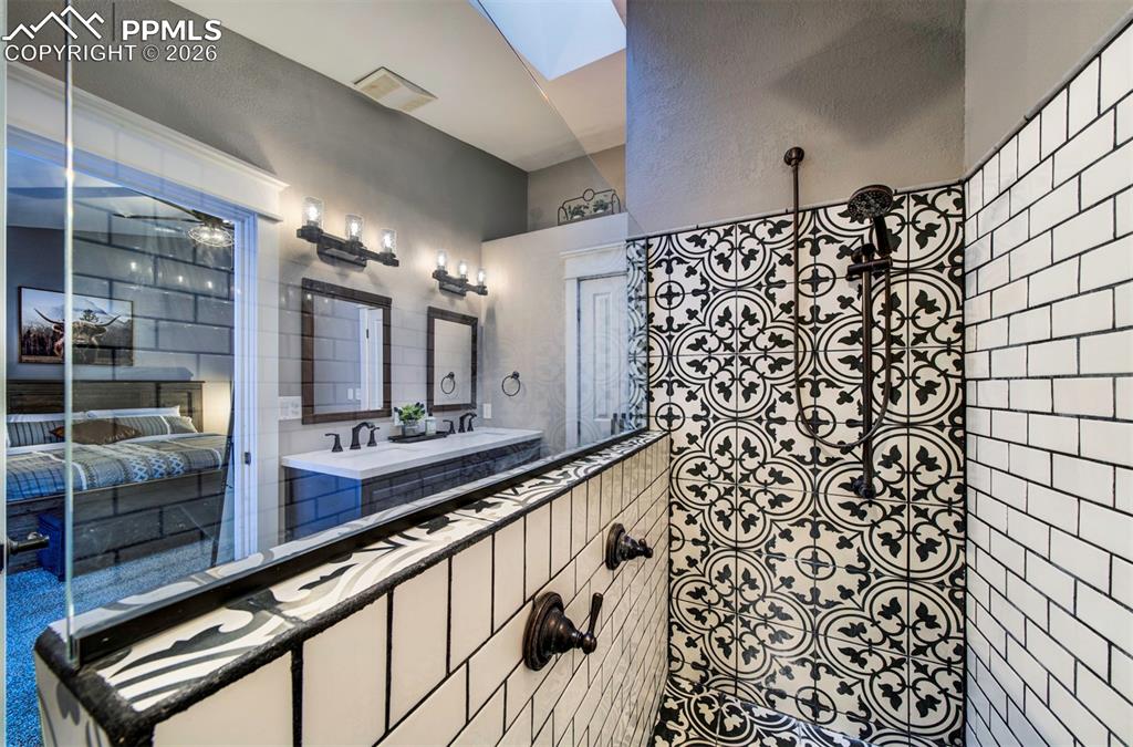 Bathroom featuring double vanity, a skylight, and a ceiling fan