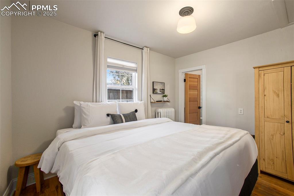 Bedroom featuring wood finished floors and radiator