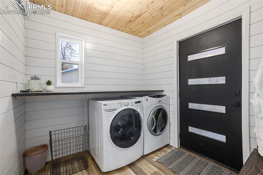 Laundry area with wood finished floors, wood walls, independent washer and dryer, and wooden ceiling