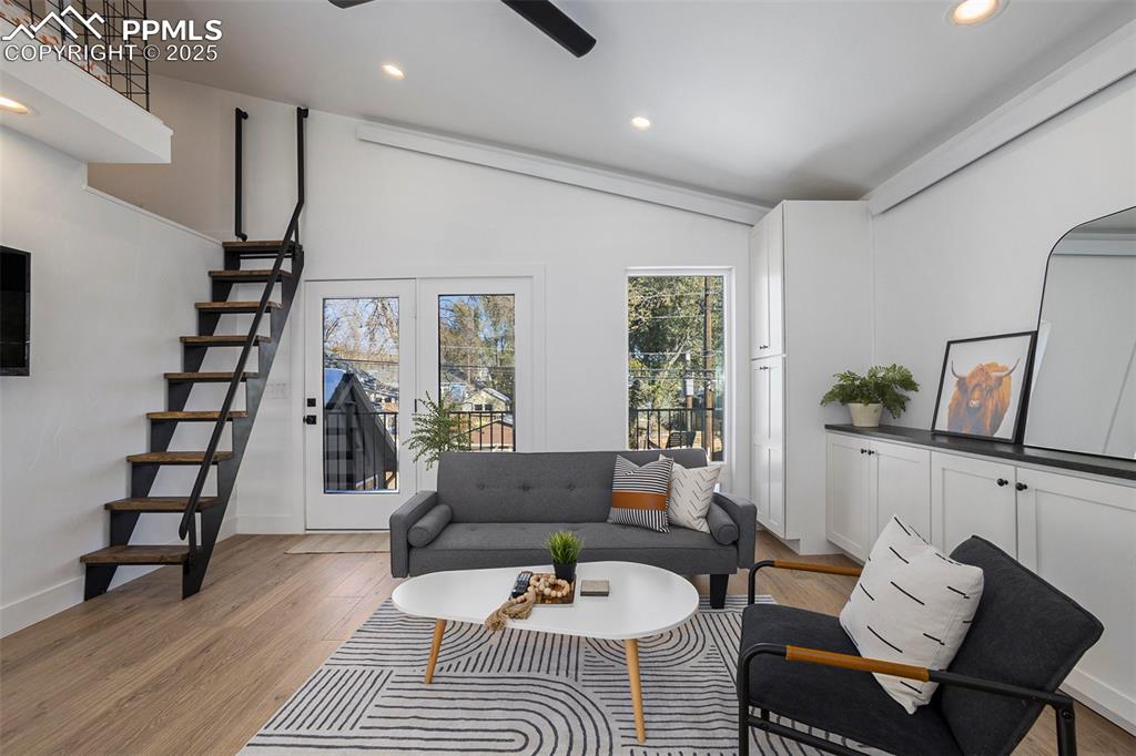 Living room with recessed lighting, vaulted ceiling, light wood-style floors, stairway, and a ceiling fan