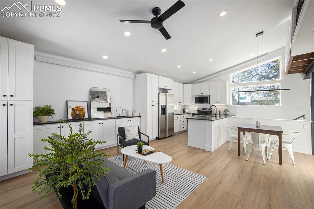 Living area with vaulted ceiling, light wood finished floors, ceiling fan, and recessed lighting