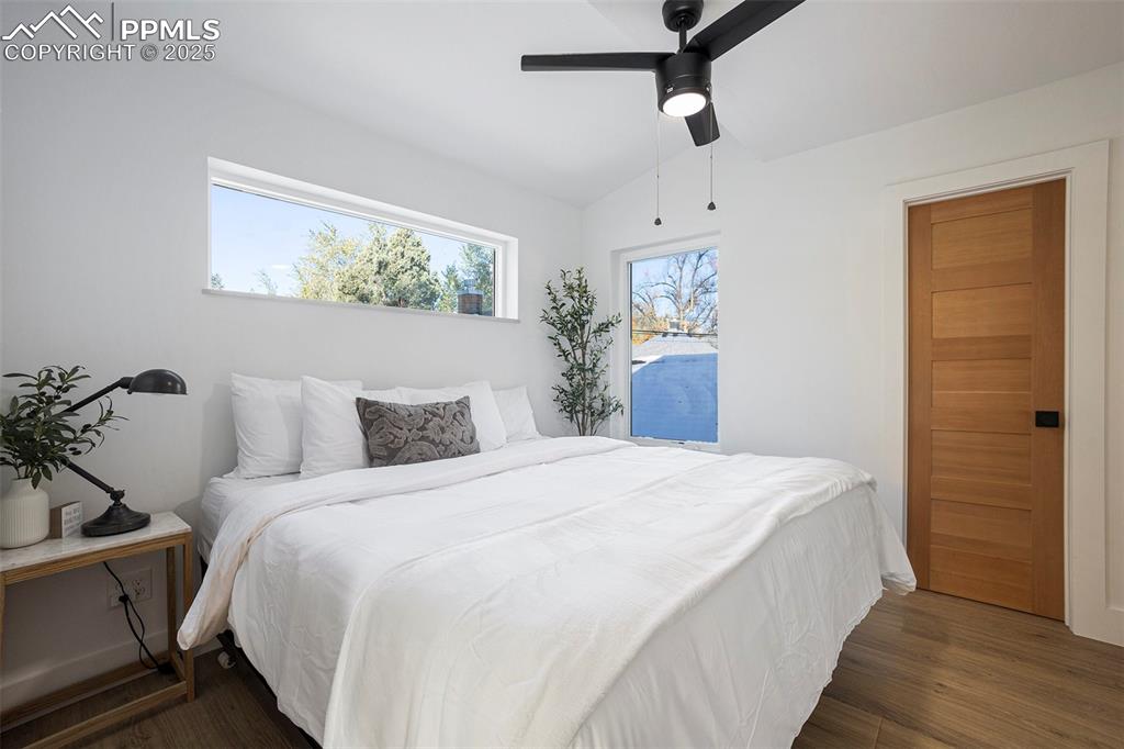 Bedroom featuring multiple windows, dark wood-style flooring, ceiling fan, and vaulted ceiling