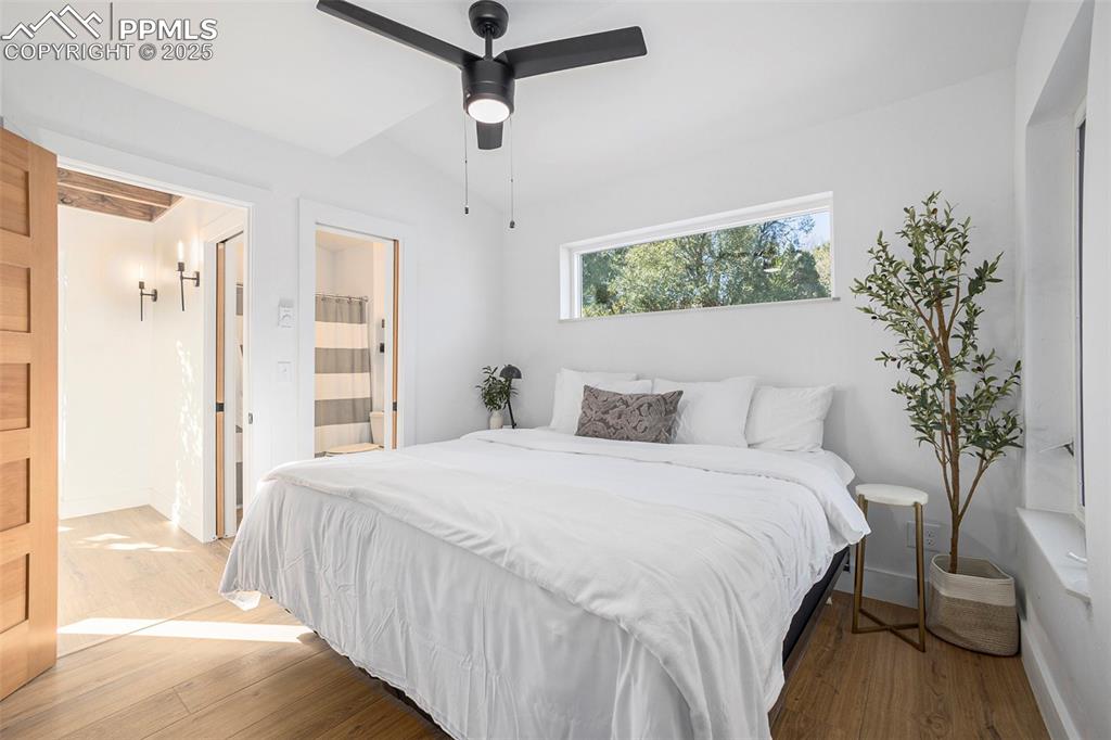 Bedroom with wood finished floors, connected bathroom, and a ceiling fan