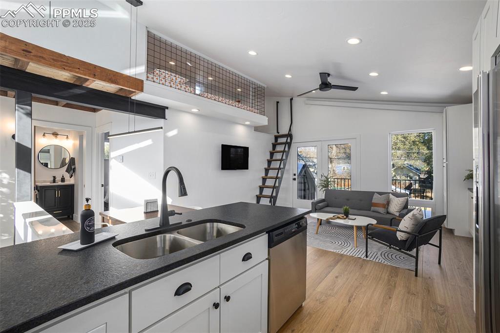 Kitchen featuring white cabinetry, lofted ceiling, light wood finished floors, appliances with stainless steel finishes, and recessed lighting